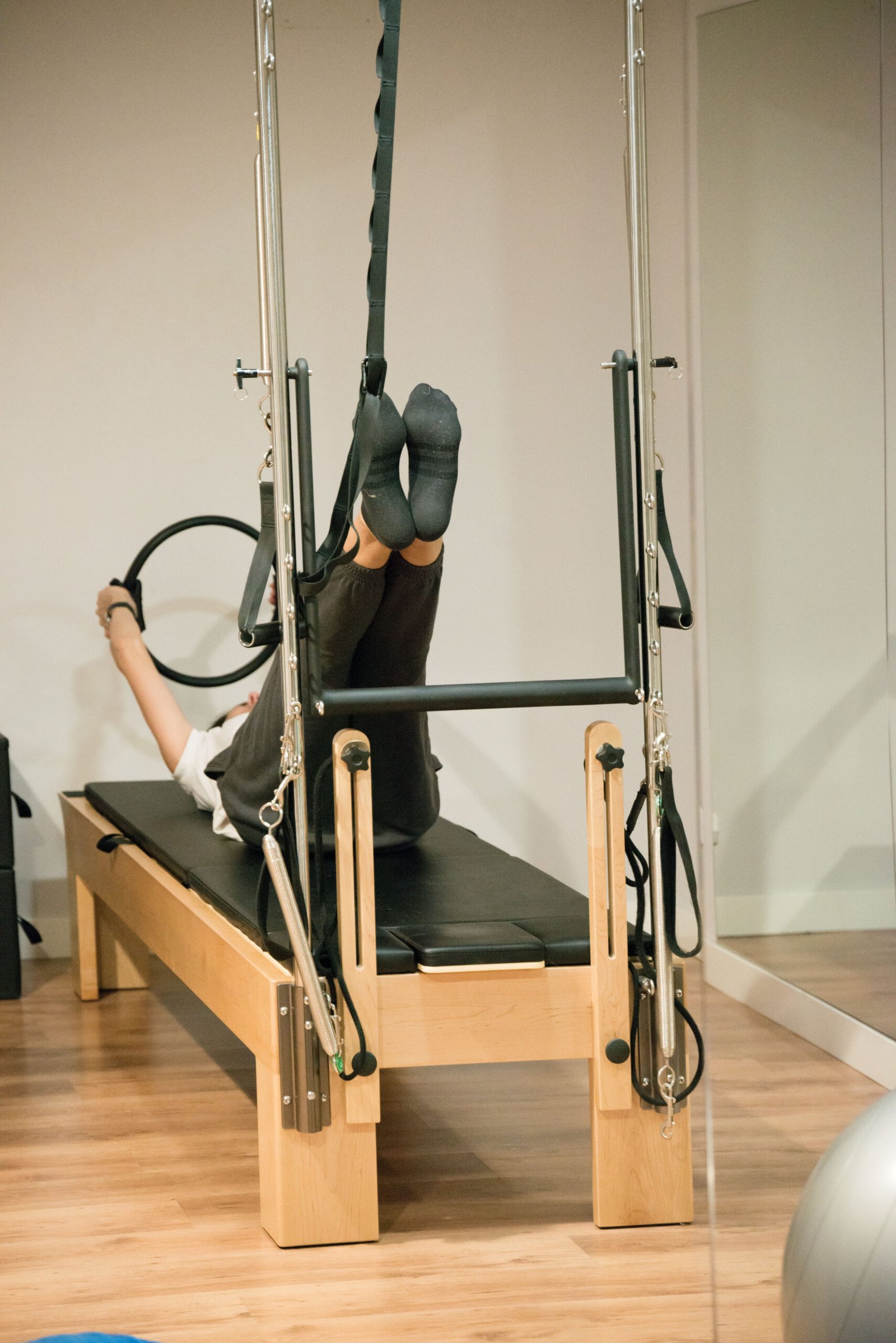 Unrecognizable woman training pilates with reformer bed. Indoors